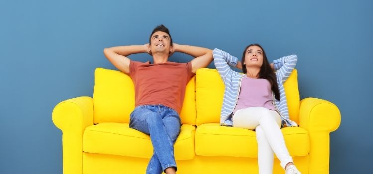 Couple Relaxing on Yellow Sofa near Color Wall