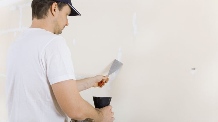 Man spackles cracks in wall