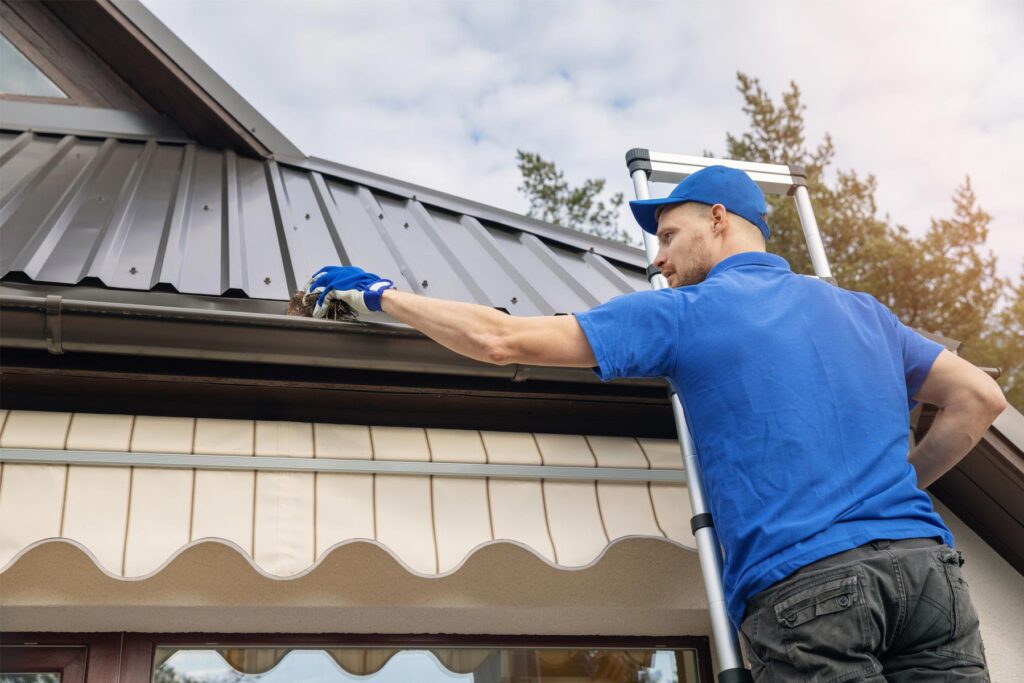 handyman cleaning gutter on a house