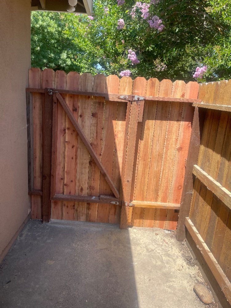 wooden fence gate repaired and installed in a home's backyard