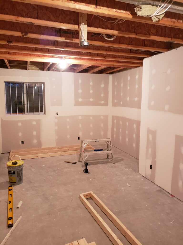 drywall being installed and repaired during a basement remodel