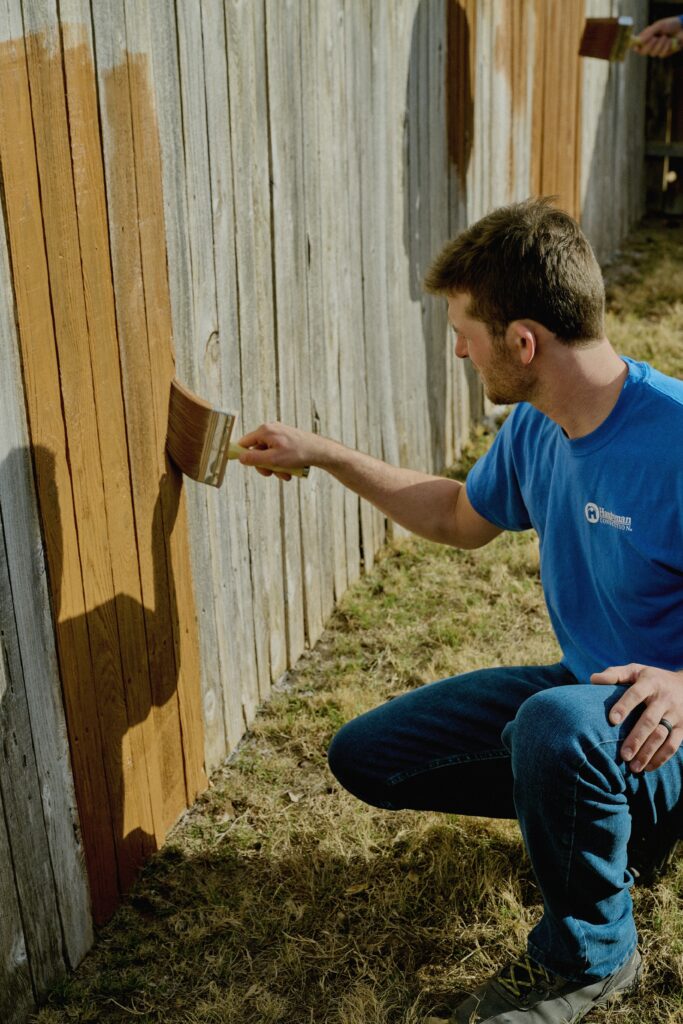 handyman in Charleston, SC, helping apply a new fence stain for a homeowner