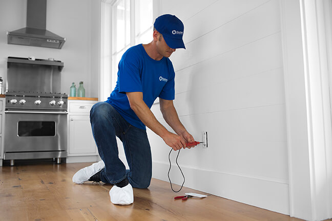 A craftsman performing an essential exterior home maintenance task to prevent costly Pasadena home repair bills.