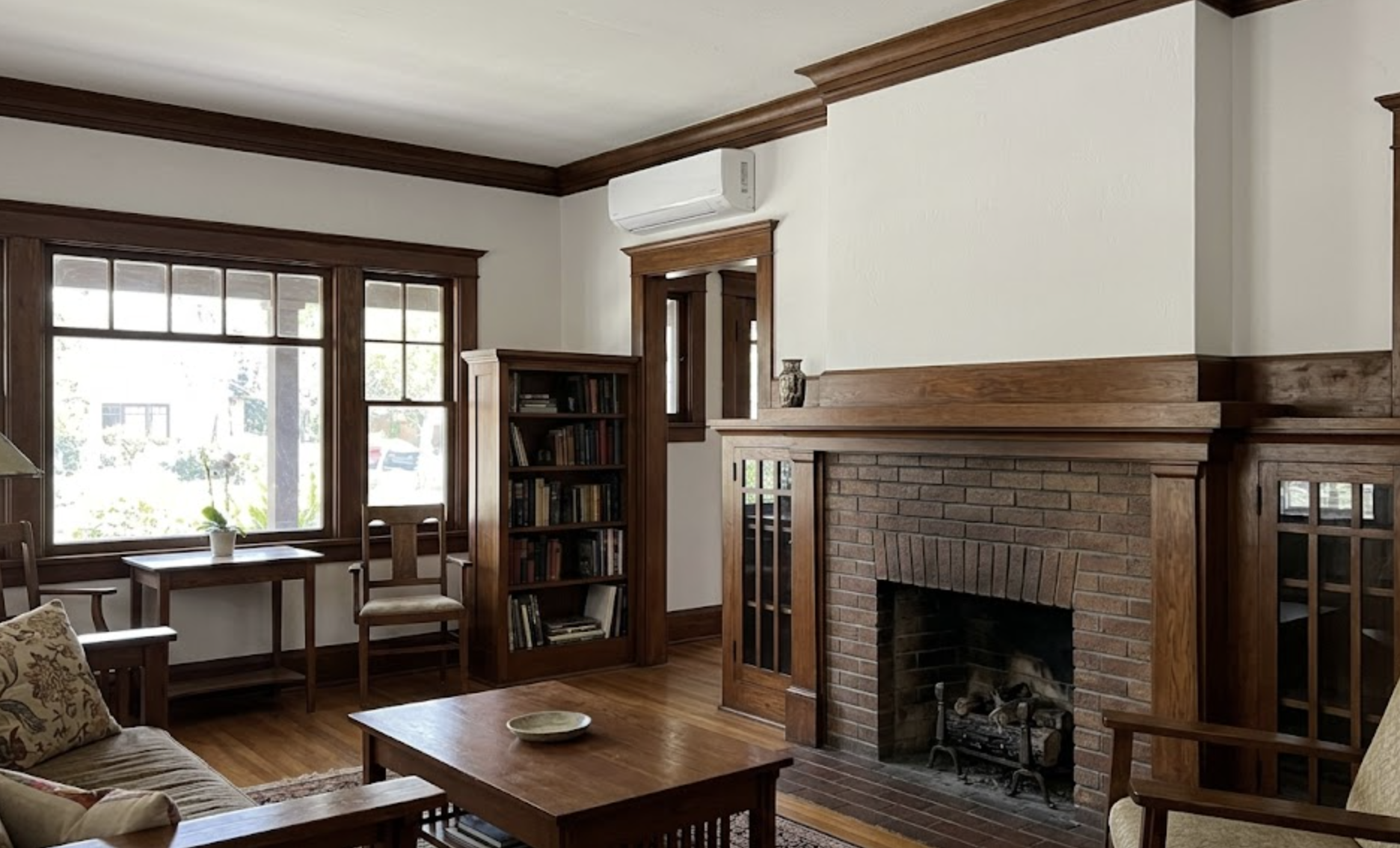 Wall-mounted ductless mini-split AC head installed in the living room of a 1920s Pasadena Craftsman bungalow with white plaster walls and original wood trim