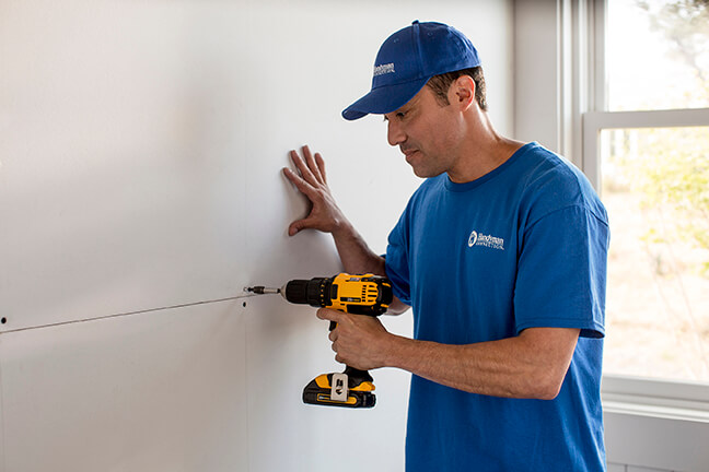 handyman using drill to install drywall