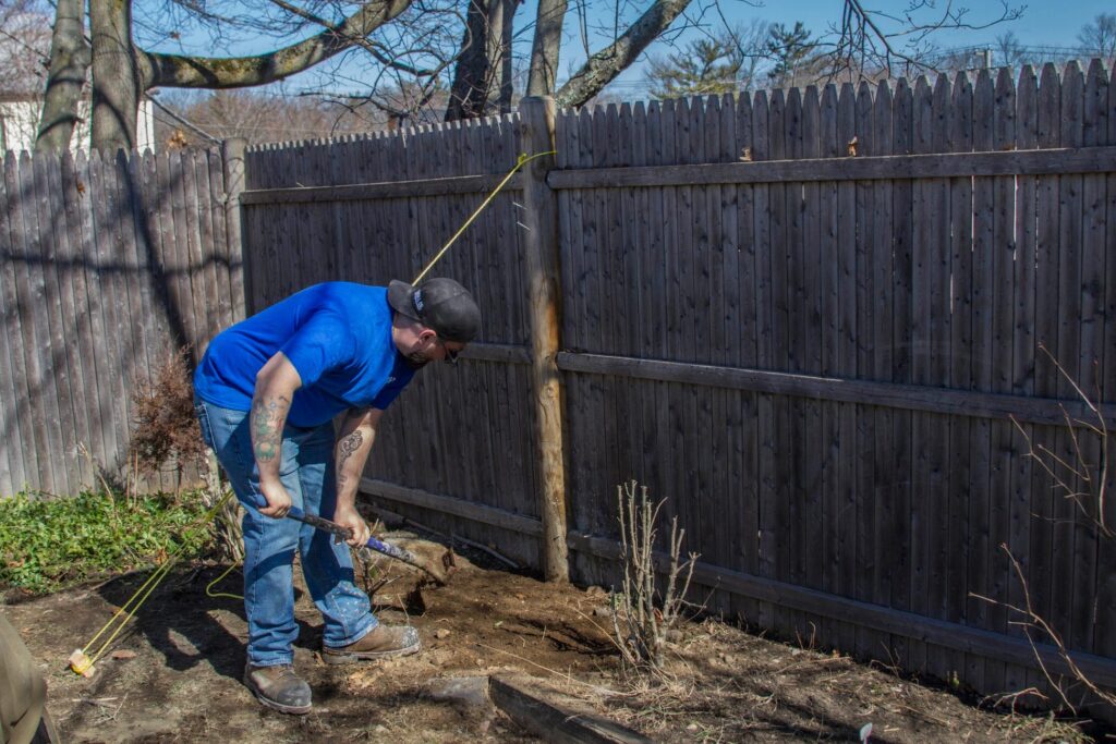 handyman helping install a new fence post in Waterford, MI