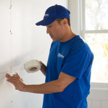 handyman using tape to repair old drywall